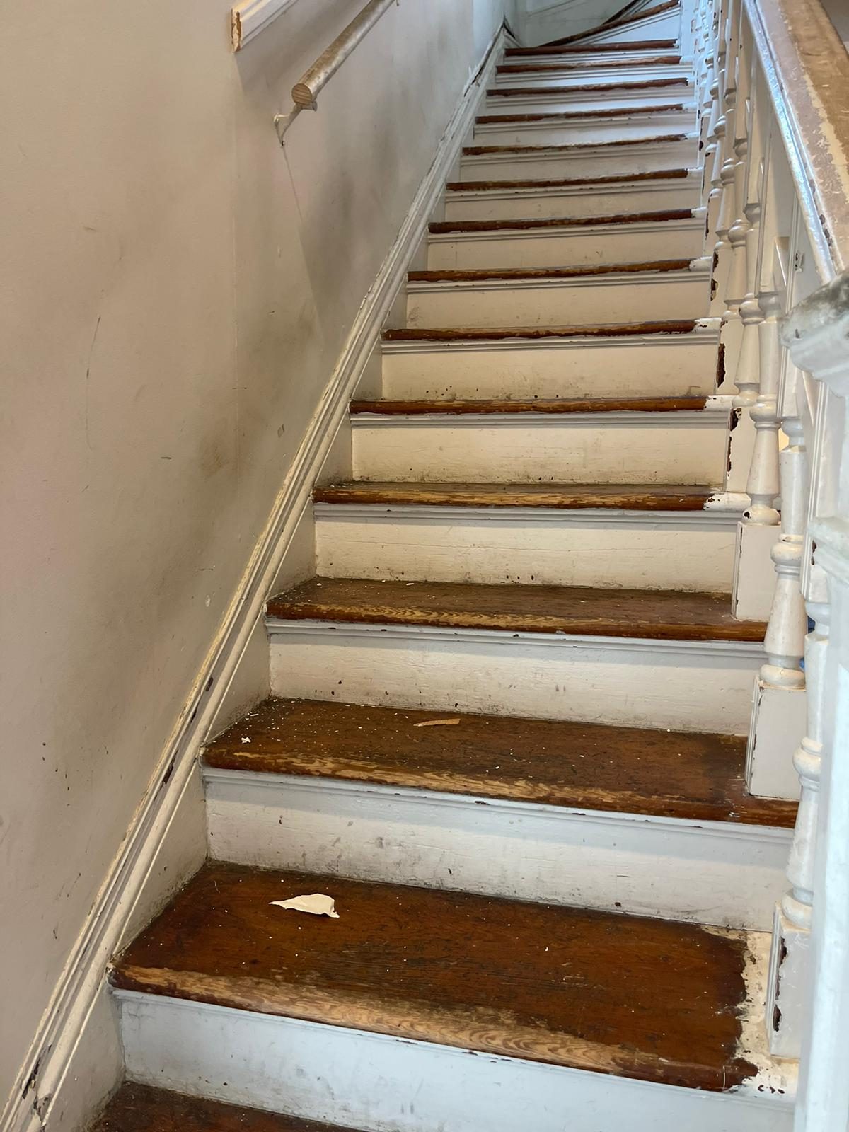 Existing stair trim and baseboard condition ahead of a repaint.
