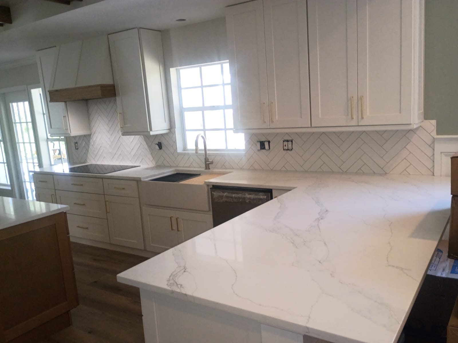 White shaker cabinets with a herringbone tile backsplash.